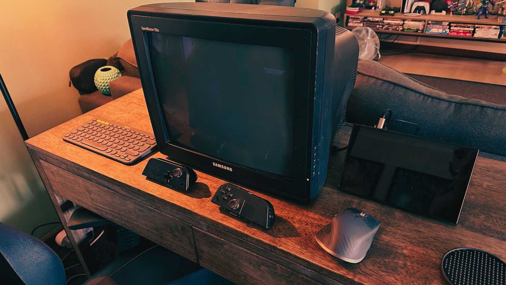 /de/images/a-crt-computer-montor-hooked-up-to-a-handheld-pc-with-a-mouse-and-keyboard-on-a-desk-and-some-controllers.jpg