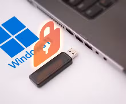 /de/images/a-laptop-with-the-windows-11-logo-next-to-it-a-usb-flash-drive-and-a-padlock-above-it.jpg