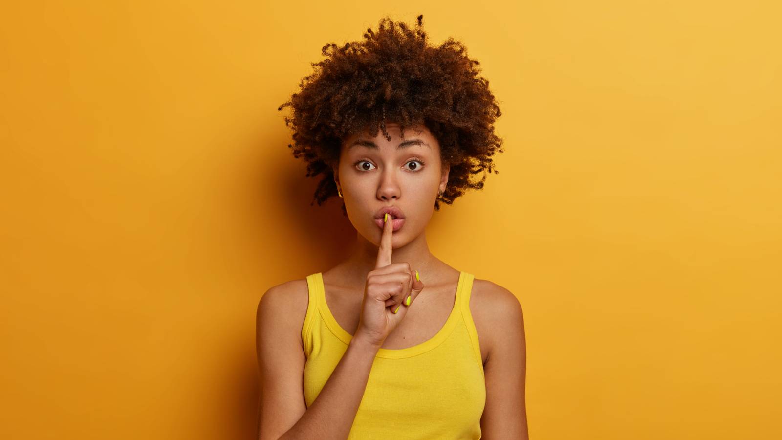 /de/images/young-woman-on-a-colorful-background-with-a-finger-to-her-mouth-in-a-shush-motion.jpg