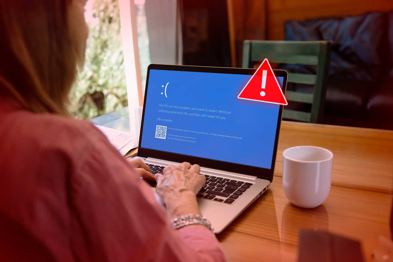 /fr/images/a-woman-using-a-laptop-with-a-blue-screen-that-appears-when-windows-randomly-shut-down-and-an-alert-symbol-on-the-front-of-the-laptop.jpg
